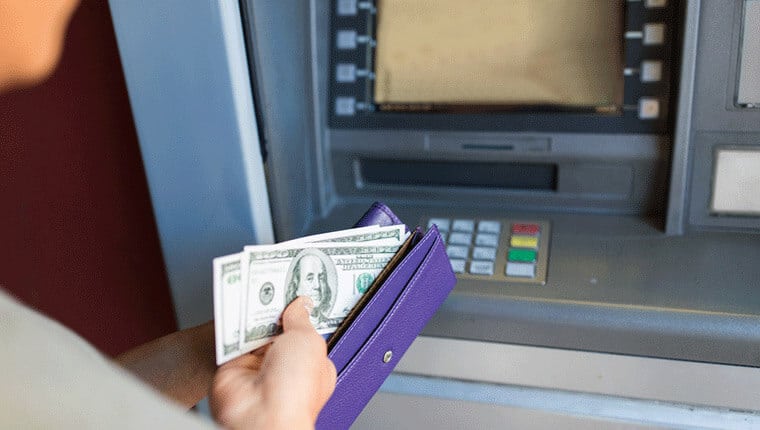 ATMの前で財布にお金を入れている人